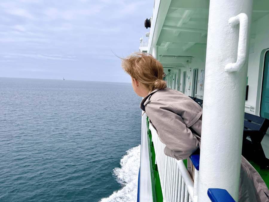Woman leaning over ships edge to sea